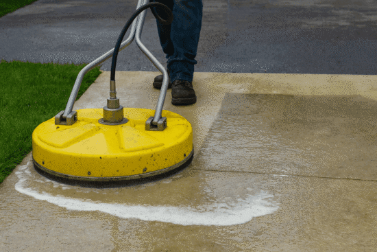 Man uses pressure washer surface cleaner on dirty driveway